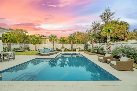a view of swimming pool with seating area and trees in the background