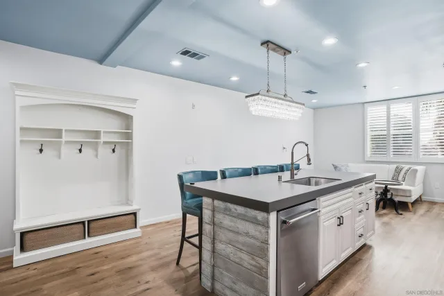 a kitchen with a stove a sink dishwasher a dining table and chairs with wooden floor