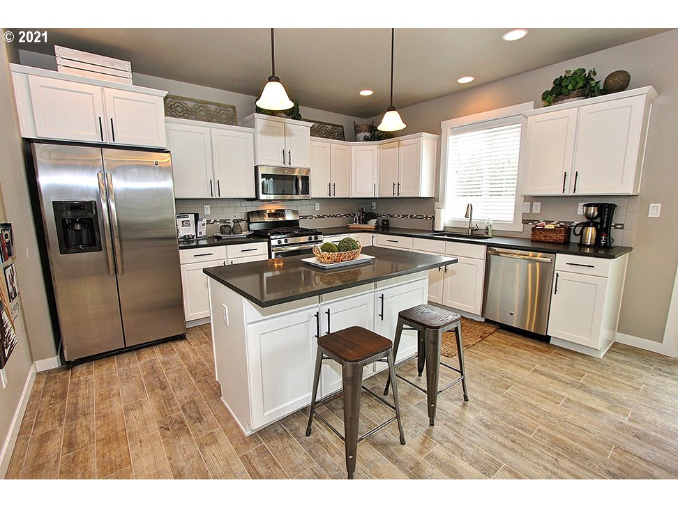5270 Squirrel Street Springfield, OR 97478 - Photo 3 of 8 a kitchen with stainless steel appliances granite countertop a sink a stove a refrigerator and island with wooden floor