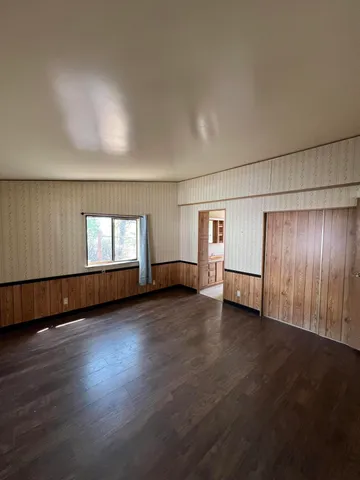 an empty room with wooden floor and windows with curtains