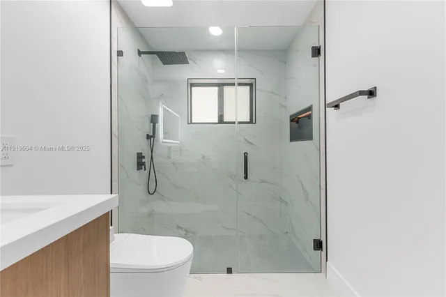 a bathroom with a granite countertop sink a toilet and shower