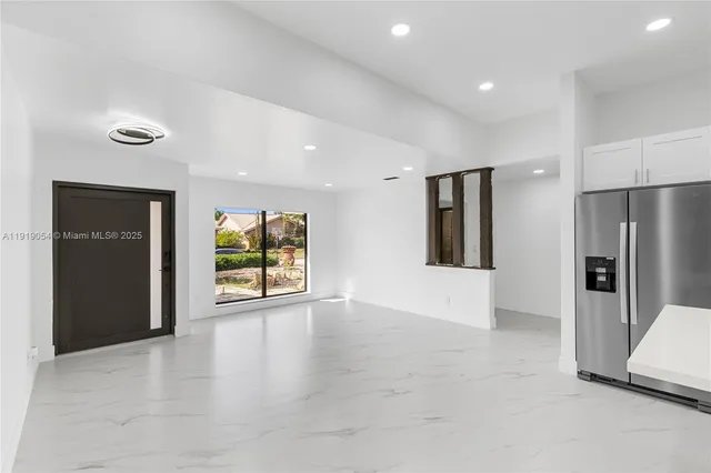 an empty room with a window and a refrigerator