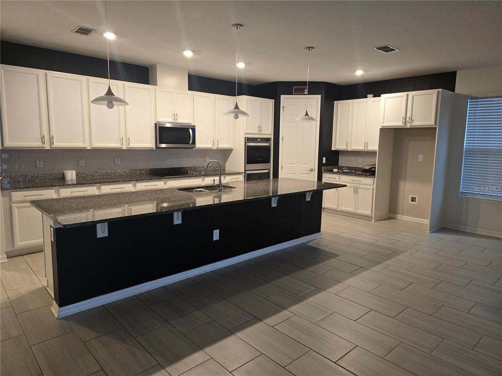 30517 Pecan Valley Loop Wesley Chapel, FL 33543 - Photo 4 of 15 a kitchen with stainless steel appliances granite countertop a refrigerator a sink and a stove