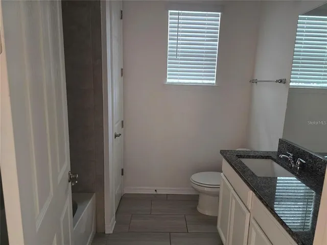 a bathroom with a granite countertop toilet and a sink