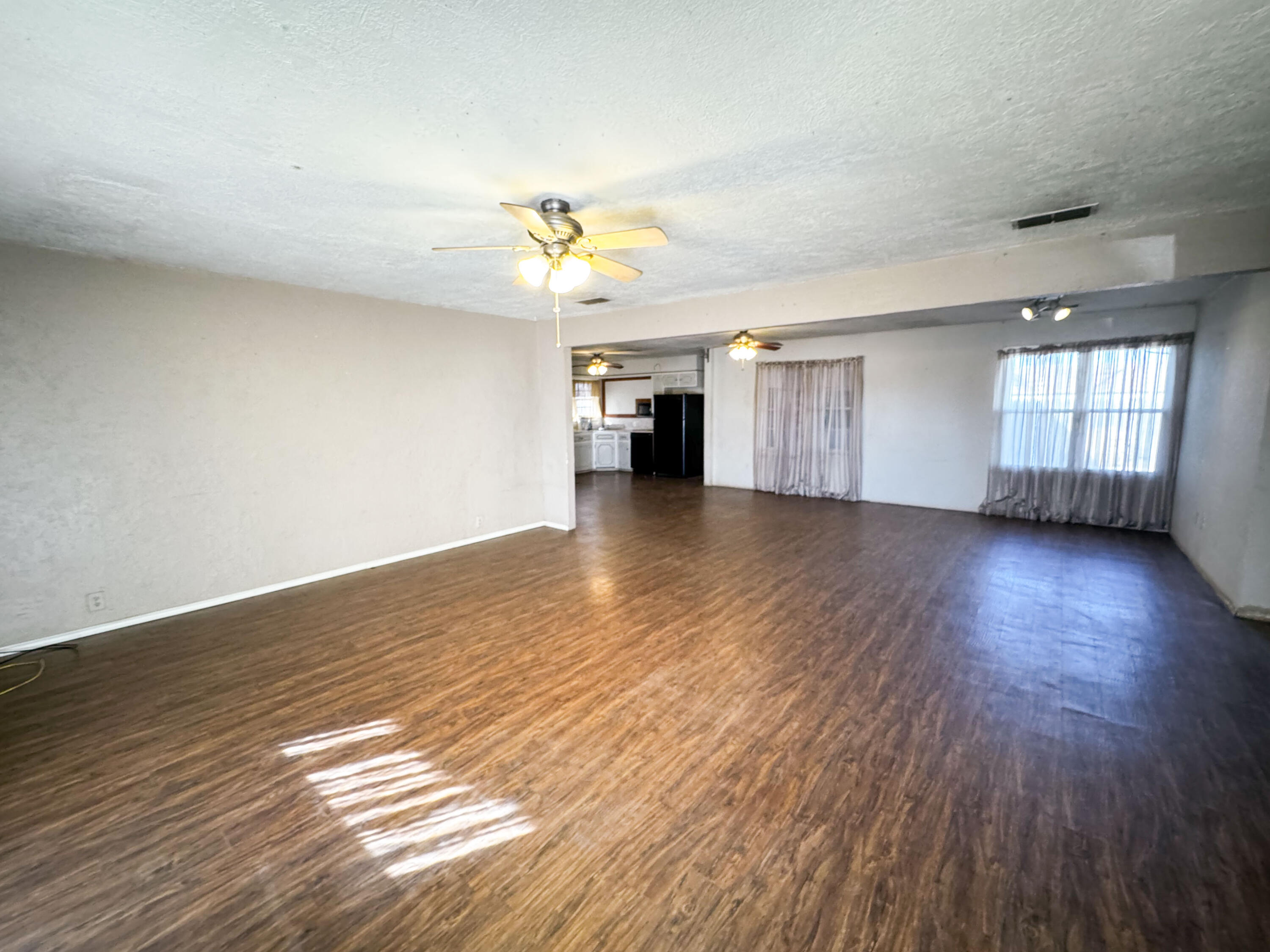733 East 13th Street Littlefield, TX 79339 - Photo 4 of 15 a view of a livingroom with wooden floor and a ceiling fan