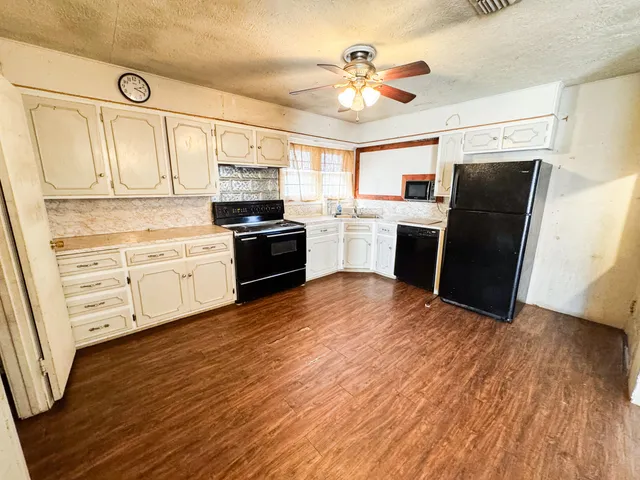 a kitchen with stainless steel appliances wooden floors and white cabinets