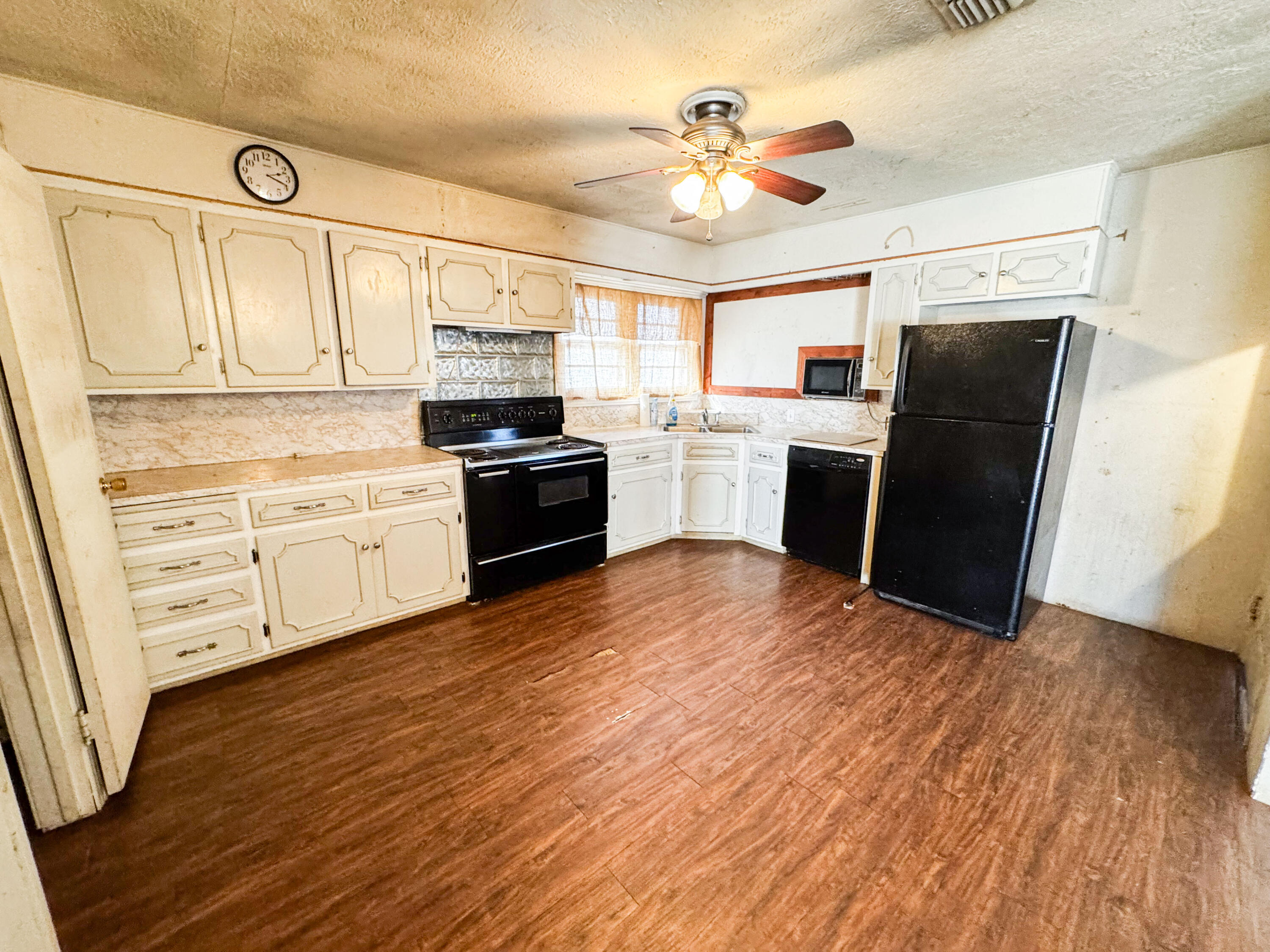 733 East 13th Street Littlefield, TX 79339 - Photo 5 of 15 a kitchen with stainless steel appliances wooden floors and white cabinets