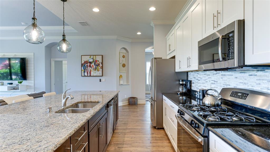 4511 Terrazza Court Lakewood Ranch, FL 34211 - Photo 13 of 65 a kitchen with stainless steel appliances granite countertop a sink a stove oven a refrigerator with wooden cabinets and floor