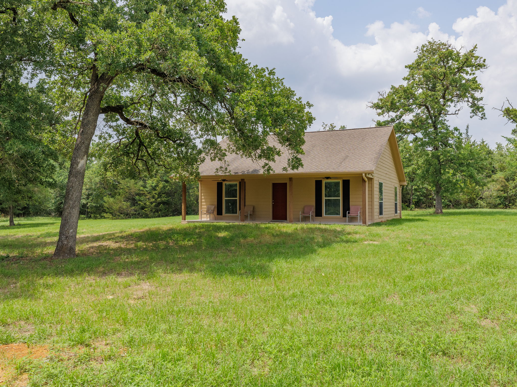 View of front of house with a shingled roof, a front yard, and a porch
