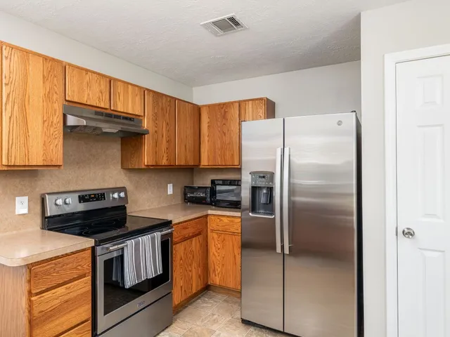 a kitchen with stainless steel appliances granite countertop a refrigerator a stove and a sink with cabinets