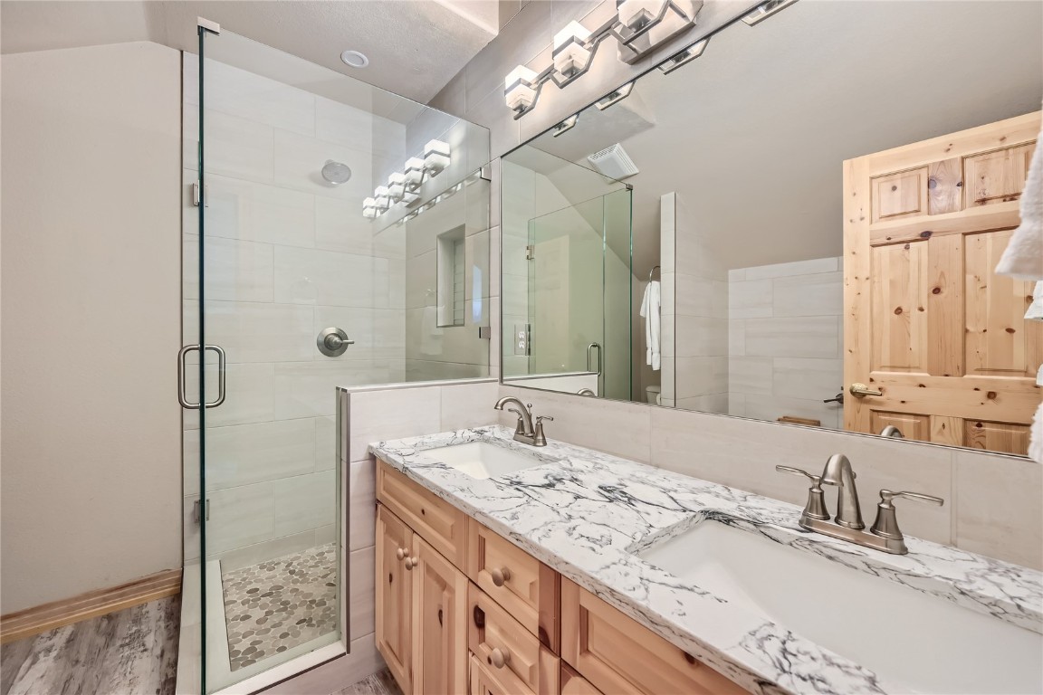 400 Kings Crown Road, Unit 400 Breckenridge, CO 80424 - Photo 14 of 40 a bathroom with a granite countertop sink a large mirror and a shower