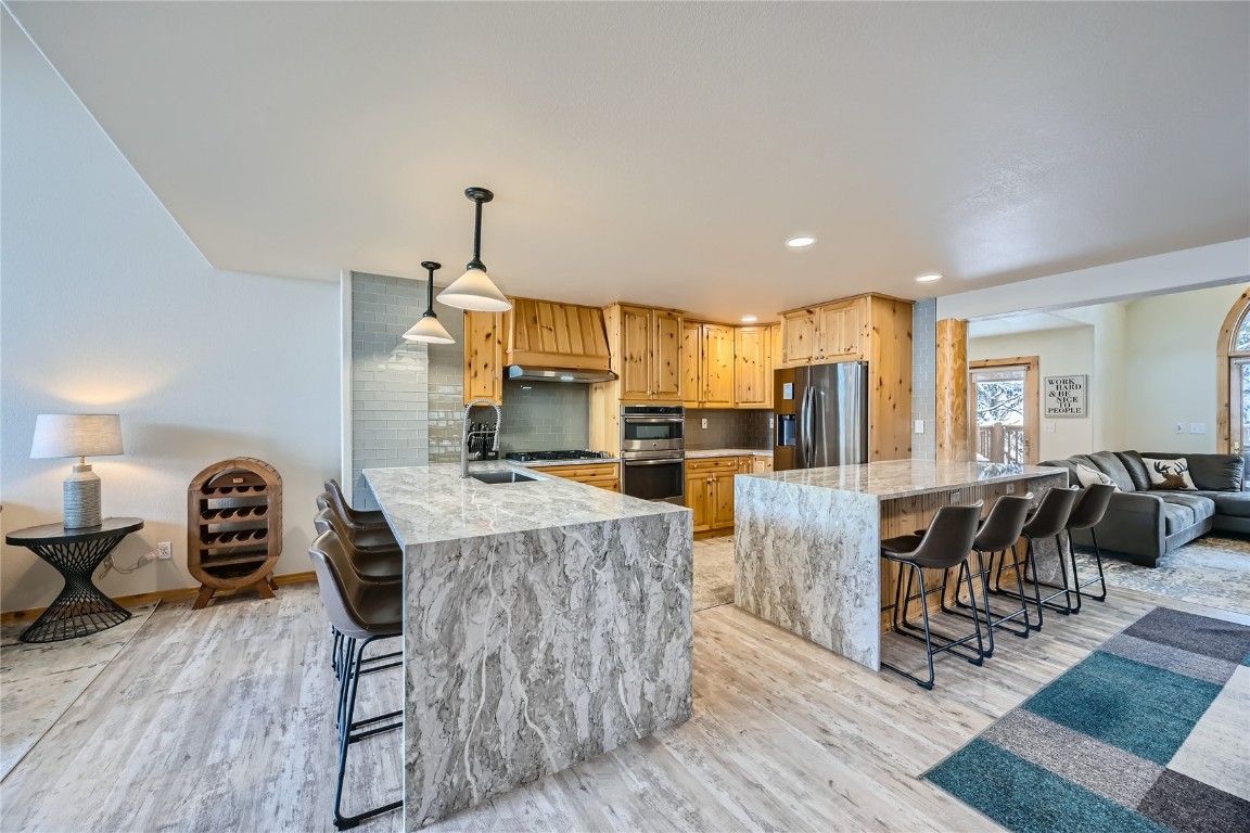 400 Kings Crown Road, Unit 400 Breckenridge, CO 80424 - Photo 3 of 40 a kitchen with kitchen island a stove a refrigerator a dining table and chairs with wooden floor