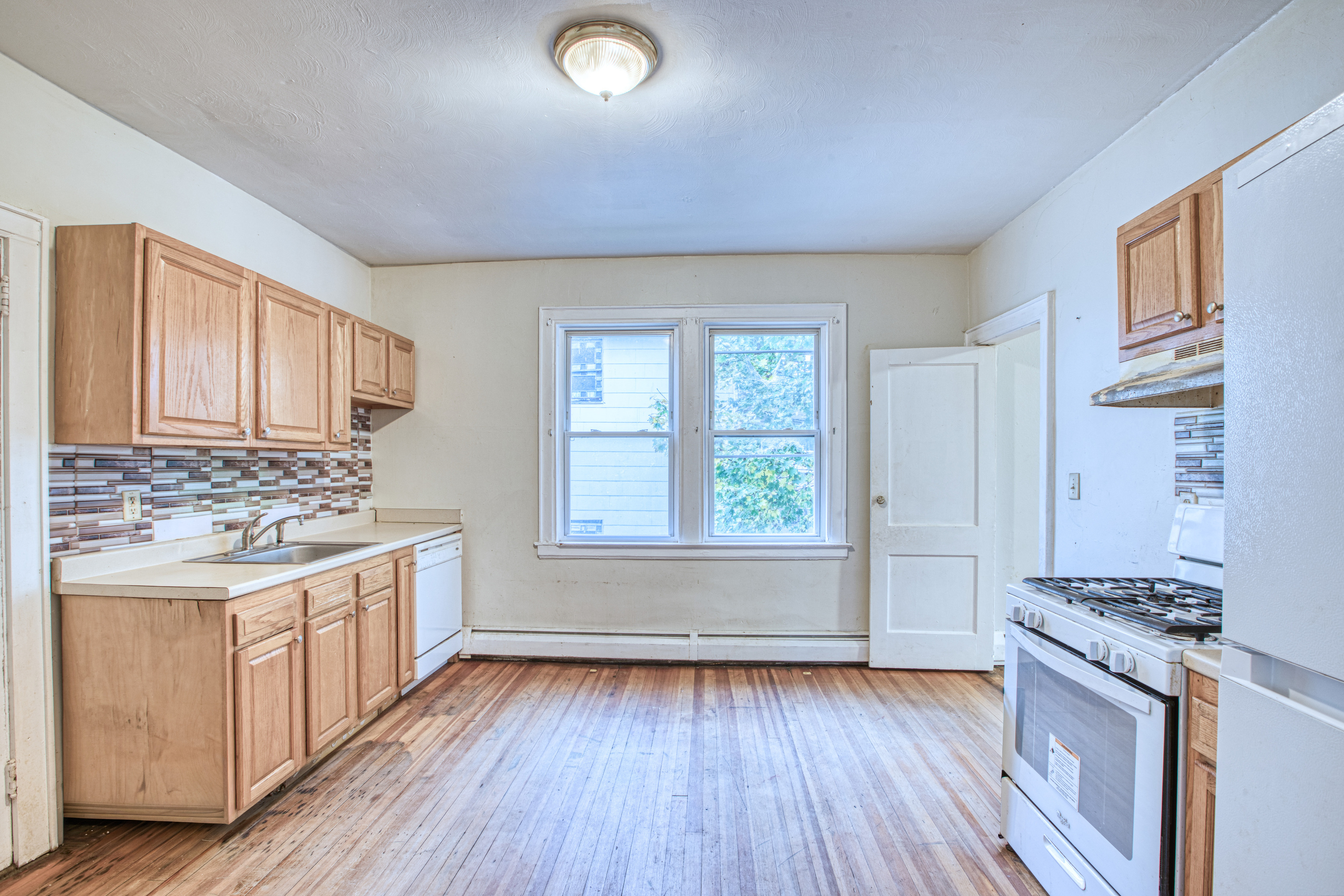 429 New Britain Avenue Hartford, CT 06106 - Photo 3 of 20 a kitchen with wooden floors and white cabinets