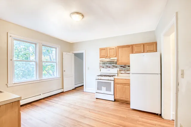 a kitchen with a refrigerator and wooden floor