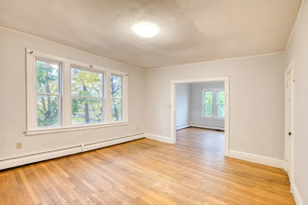 an empty room with wooden floor and windows