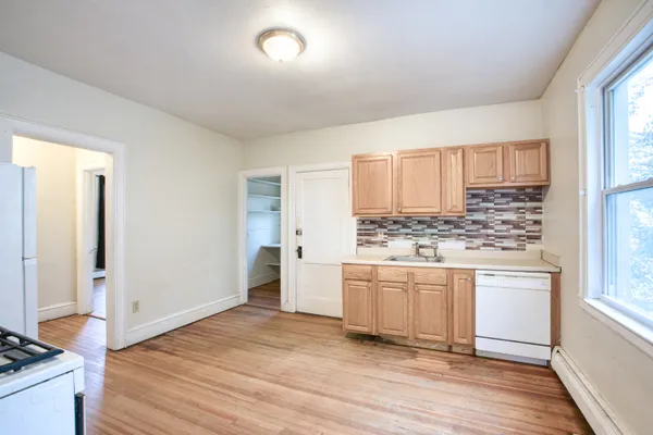 a room with kitchen island white cabinets and wooden floor