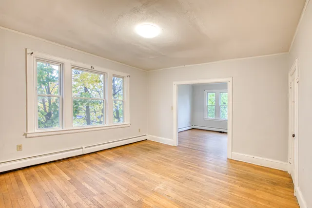 an empty room with wooden floor and windows