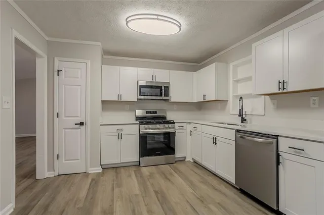 a kitchen with cabinets stainless steel appliances a sink and wooden floor