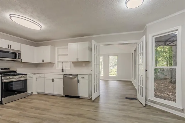 a kitchen with stainless steel appliances granite countertop a stove top oven a sink and white cabinets