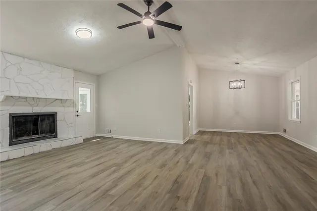 an empty room with wooden floor fireplace and windows