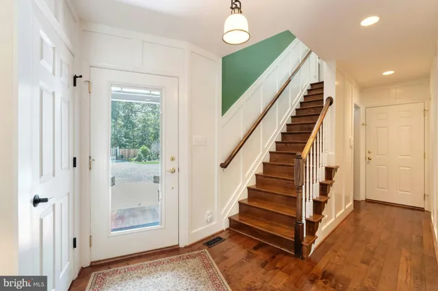 a kitchen with stainless steel appliances granite countertop a stove a refrigerator a kitchen island and chairs with wooden floor