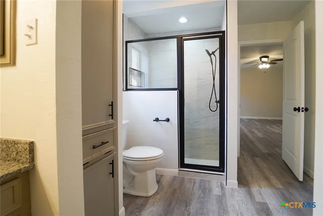 a bathroom with a glass door shower and a toilet