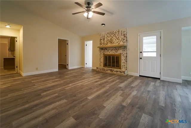 a view of empty room with wooden floor and fireplace