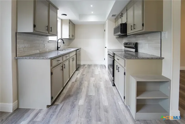 a kitchen with stainless steel appliances granite countertop wooden cabinets a stove top oven a sink and dishwasher