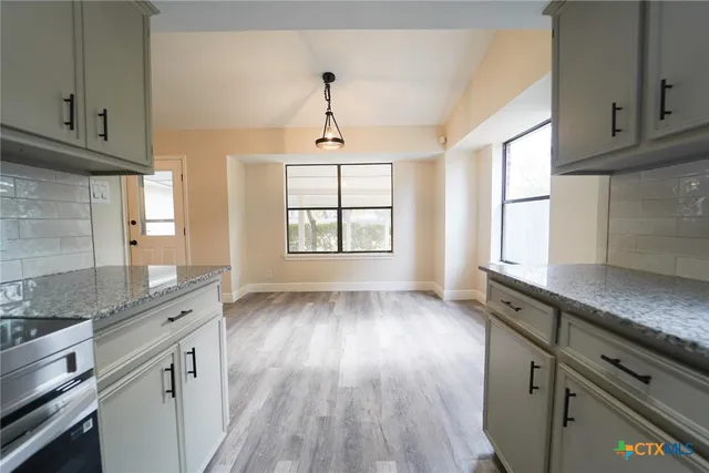 a kitchen with granite countertop wooden floors and white cabinets