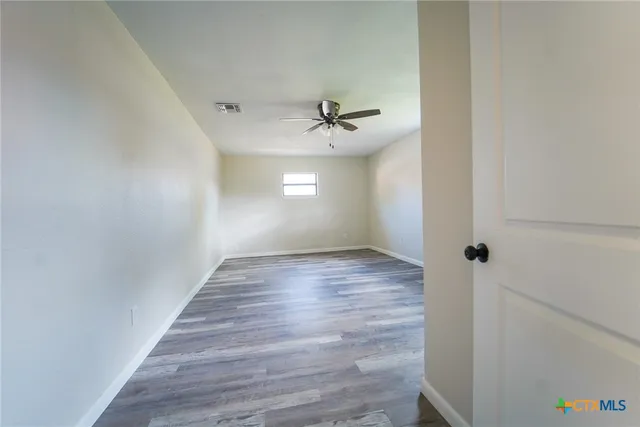 a view of a hallway with wooden floor and a ceiling fan