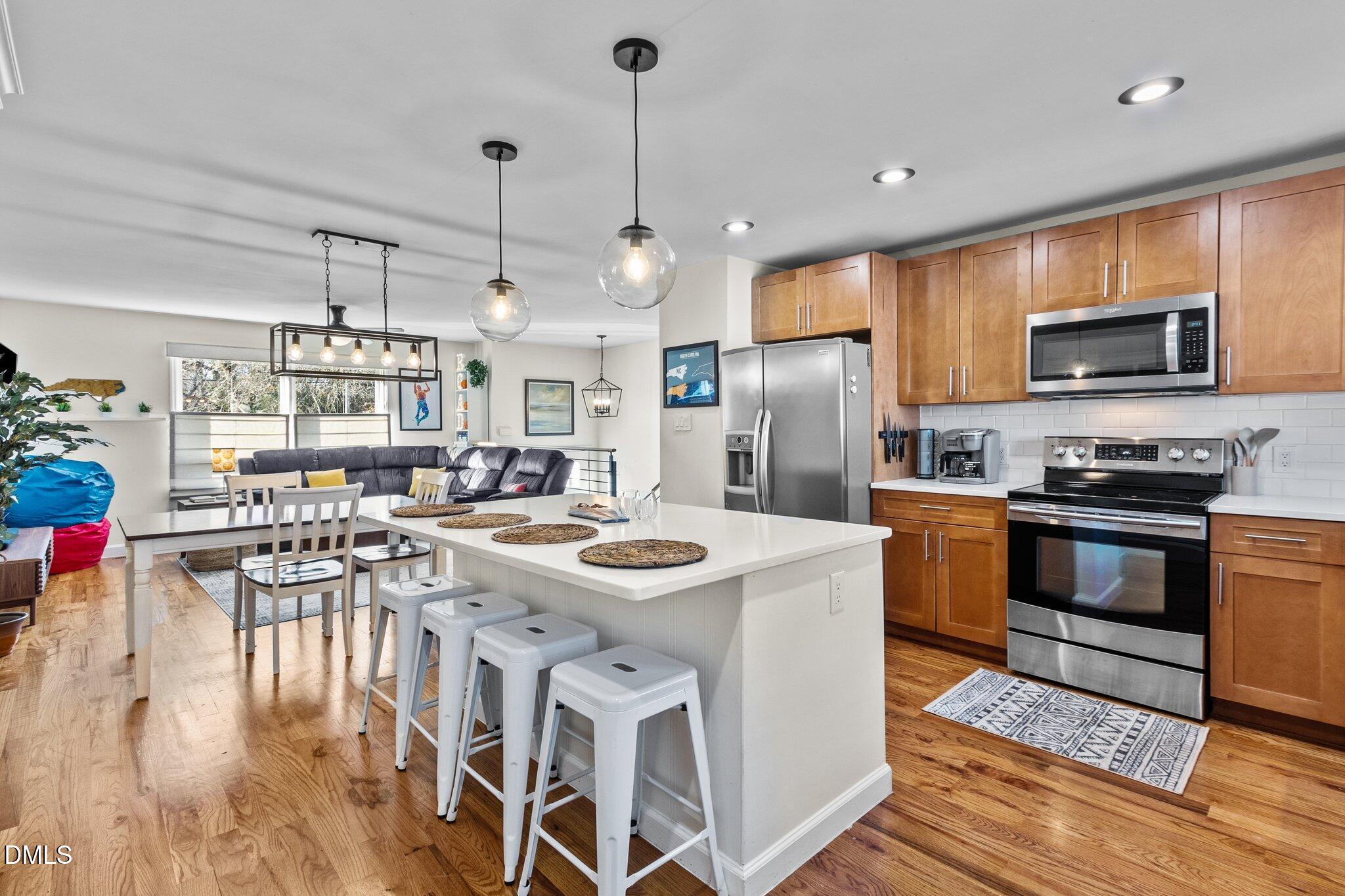 1023 Holmes Street Raleigh, NC 27601 - Photo 12 of 41 a kitchen with stainless steel appliances kitchen island granite countertop a sink a stove a refrigerator and island with wooden floor