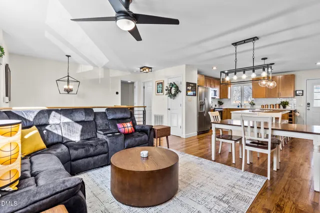 a kitchen with stainless steel appliances kitchen island granite countertop a sink a stove a refrigerator and island with wooden floor