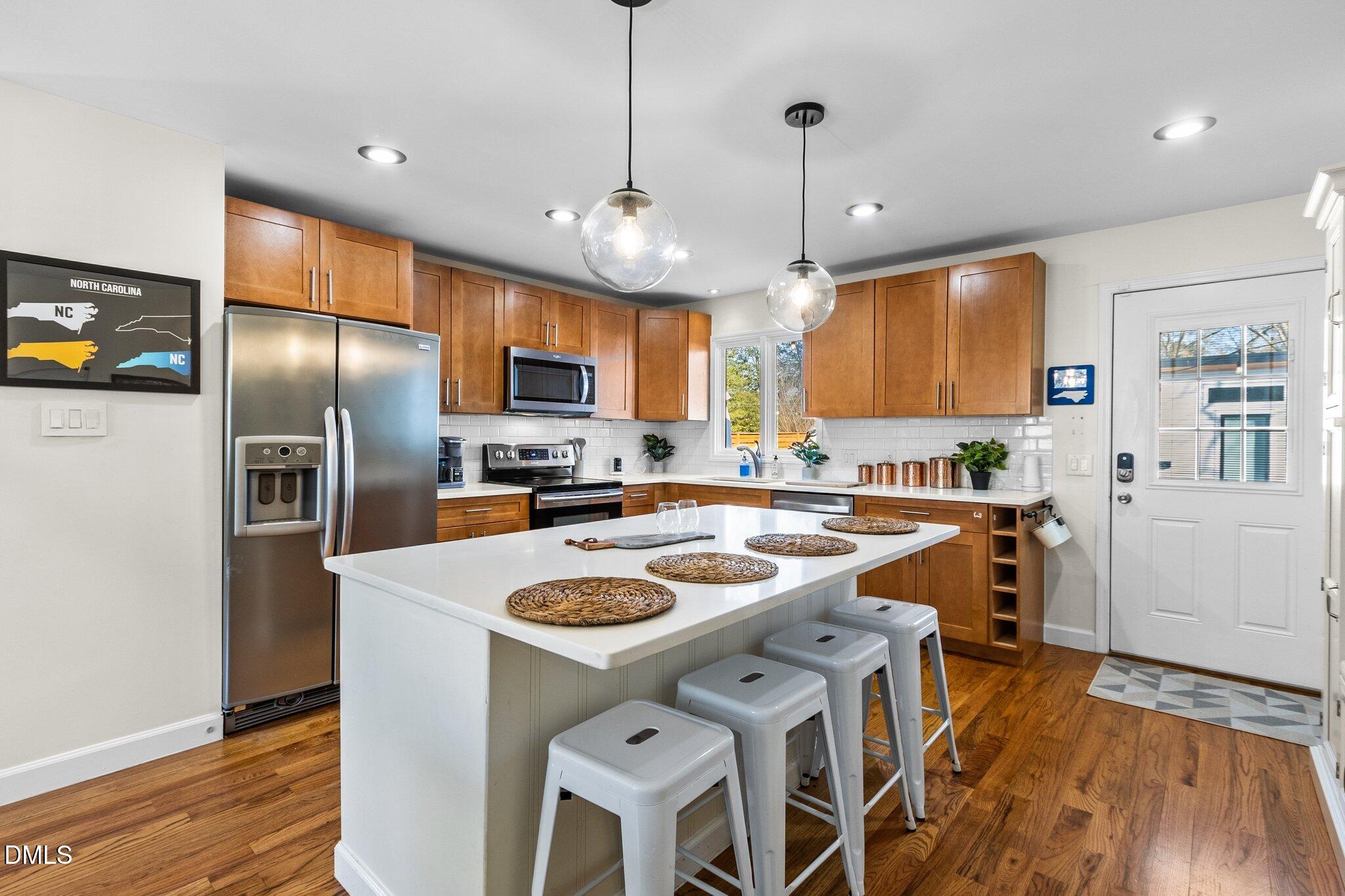 1023 Holmes Street Raleigh, NC 27601 - Photo 9 of 41 a kitchen with stainless steel appliances granite countertop a refrigerator a sink dishwasher a stove and a dining table with wooden floor