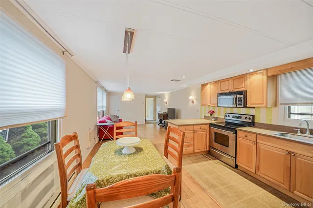 a kitchen with stainless steel appliances granite countertop a stove top oven a sink dishwasher a dining table and chairs with wooden floor