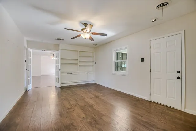 a view of empty room with wooden floor and ceiling fan