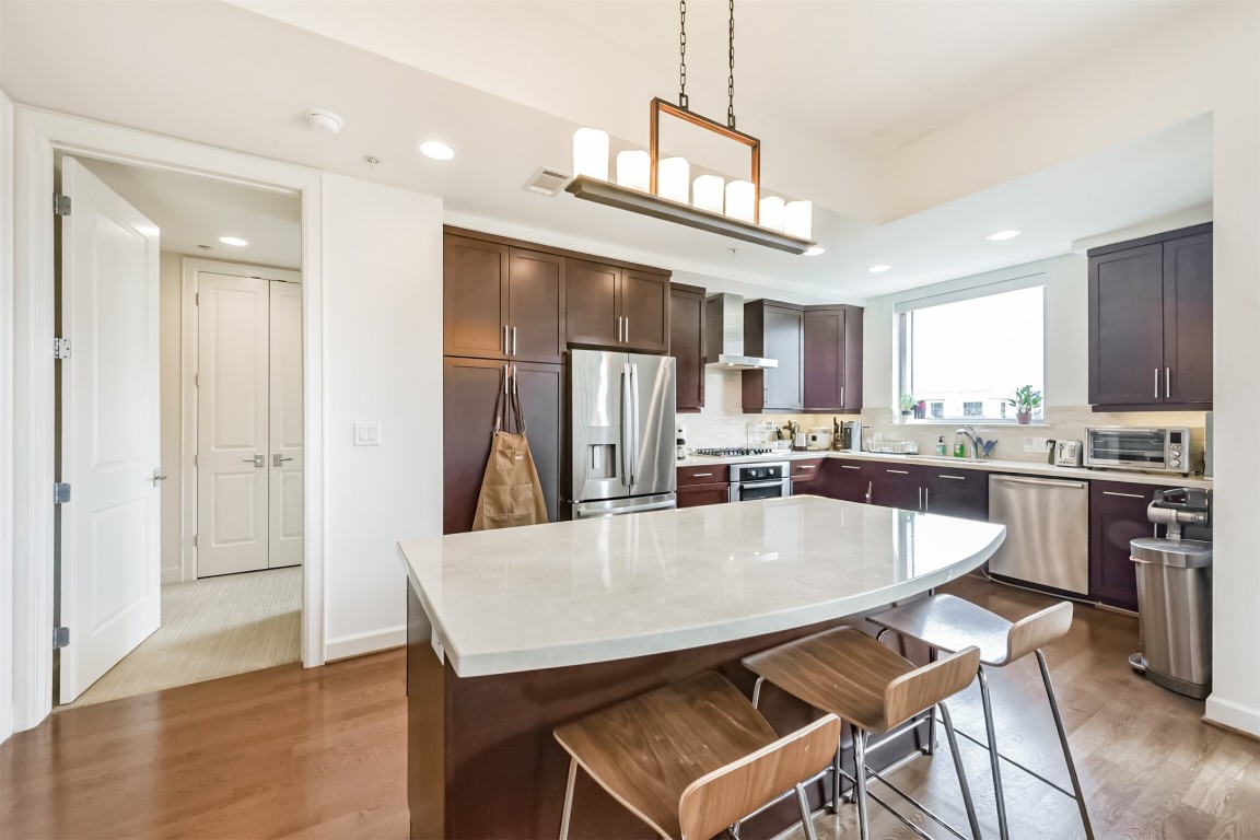 2207 Bancroft Lane, Unit 706 Houston, TX 77027 - Photo 8 of 43 a kitchen with stainless steel appliances kitchen island granite countertop a refrigerator a stove top oven a sink dishwasher and white cabinets with wooden floor