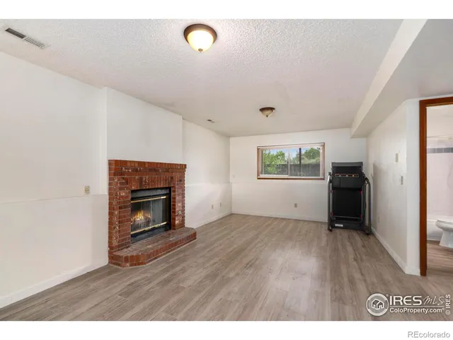 a view of empty room with wooden floor and fireplace