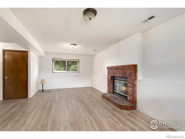 a view of an empty room with a fireplace and a window