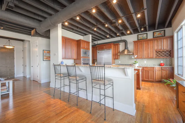 a kitchen with stainless steel appliances granite countertop a table chairs refrigerator and wooden floor