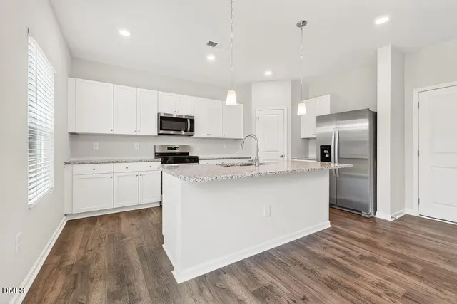 a kitchen with kitchen island a sink a center island stainless steel appliances and a window