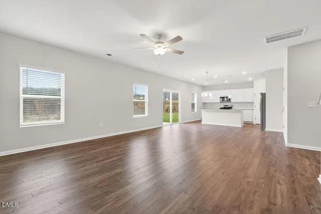 an empty room with wooden floor ceiling fan and window