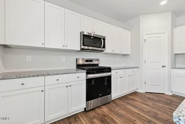 a kitchen with stainless steel appliances granite countertop a stove a sink and a microwave