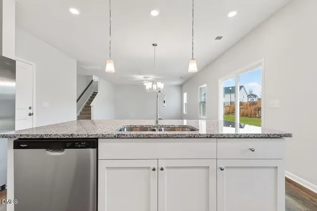 a kitchen with granite countertop white cabinets and stainless steel appliances