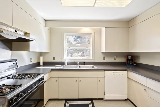 a kitchen with granite countertop a sink stove and cabinets