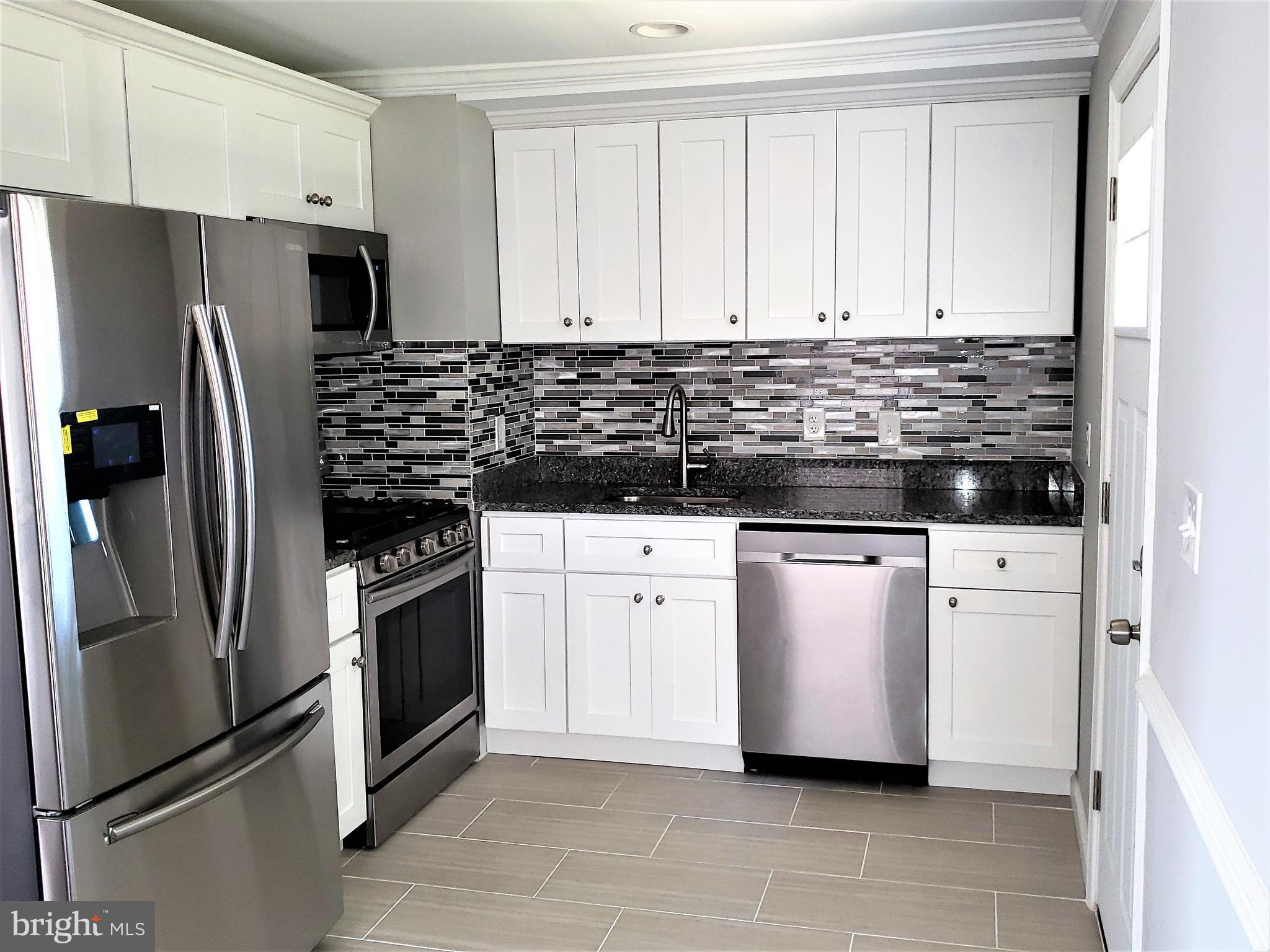 4709 68th Avenue Hyattsville, MD 20784 - Photo 5 of 30 a kitchen with white cabinets and stainless steel appliances