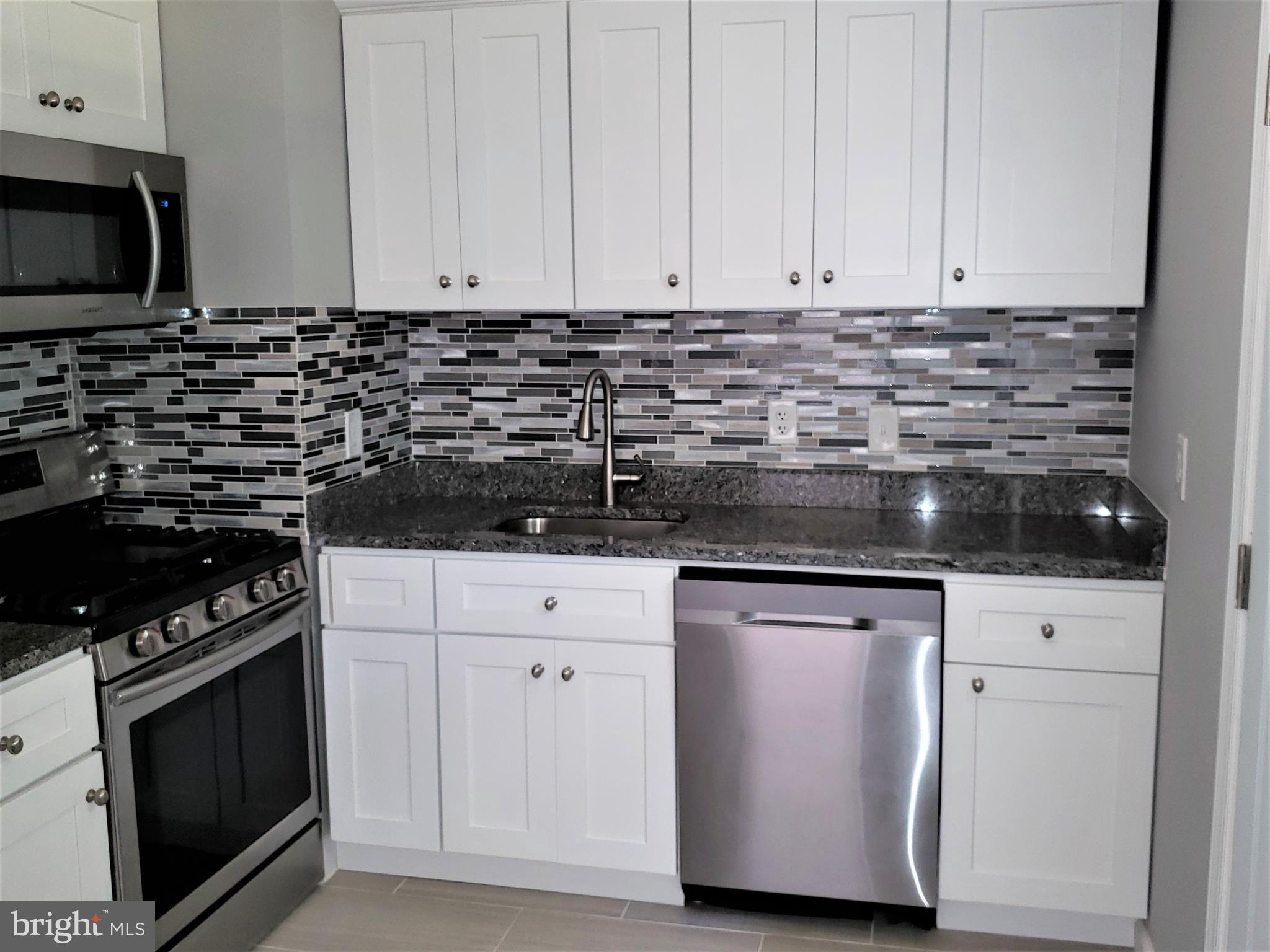 4709 68th Avenue Hyattsville, MD 20784 - Photo 6 of 30 a kitchen with granite countertop white cabinets and stainless steel appliances