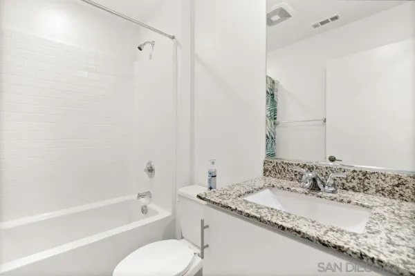 a bathroom with a granite countertop tub sink and mirror