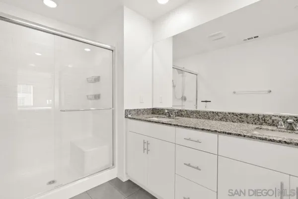 a bathroom with a granite countertop sink a mirror and shower