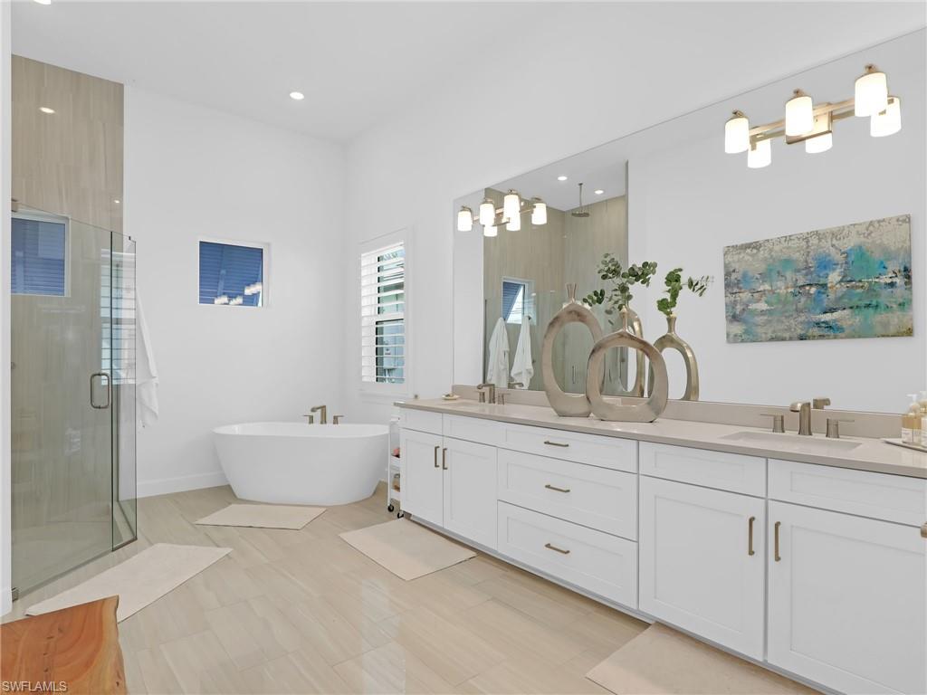 15432 Turin Drive Naples, FL 34114 - Photo 25 of 45 a spacious bathroom with double sink a toilet a large mirror and shower