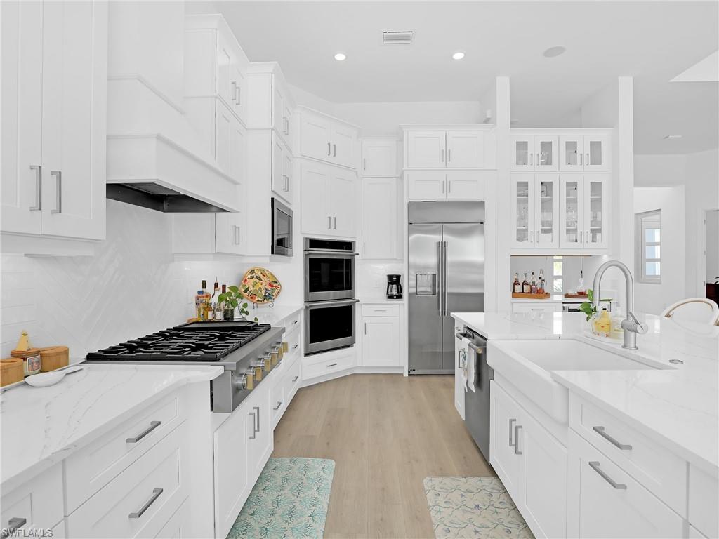 15432 Turin Drive Naples, FL 34114 - Photo 8 of 45 a kitchen with white cabinets and appliances